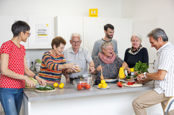 eine Gruppe fröhlicher erwachsener Menschen kocht gemeinsam